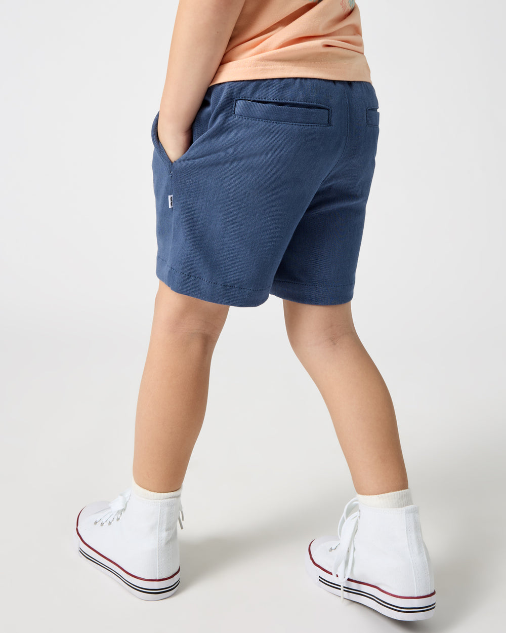 Back view of boy wearing the Vintage Navy Chino Shorts with high top sneakers