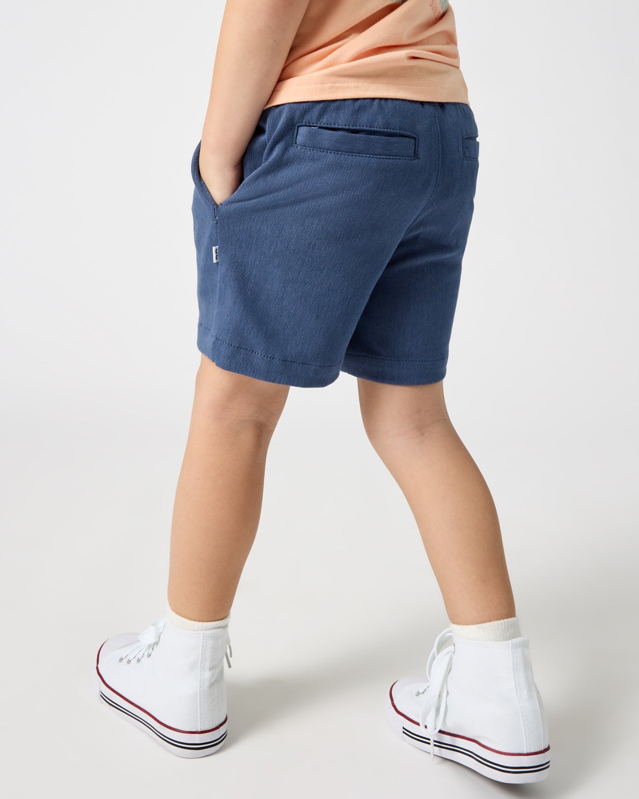 Back view of boy wearing the Vintage Navy Chino Shorts with high top sneakers