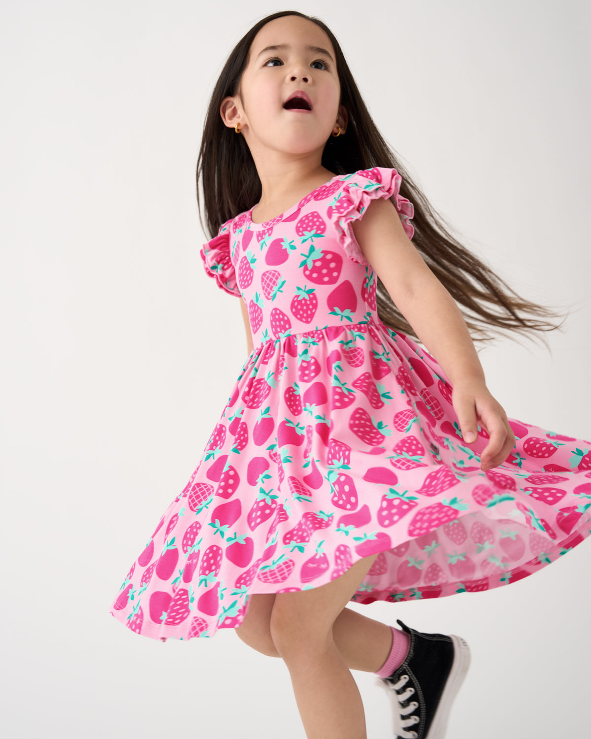 Child in motion wearing the Sweet Strawberries Flutter Twirl Dress