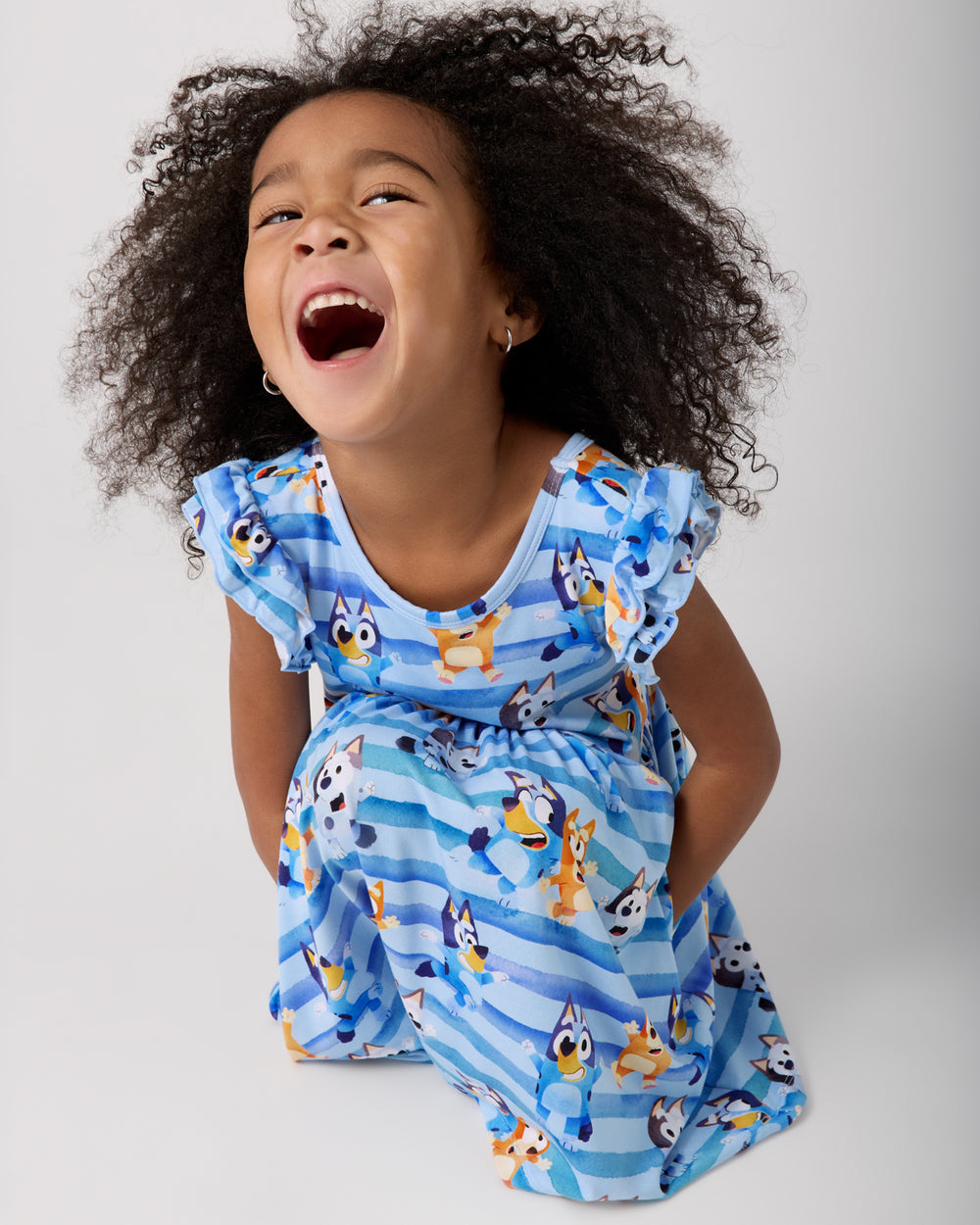 Crouching girl wearing the Bluey Dance All Day Flutter Skater Dress
