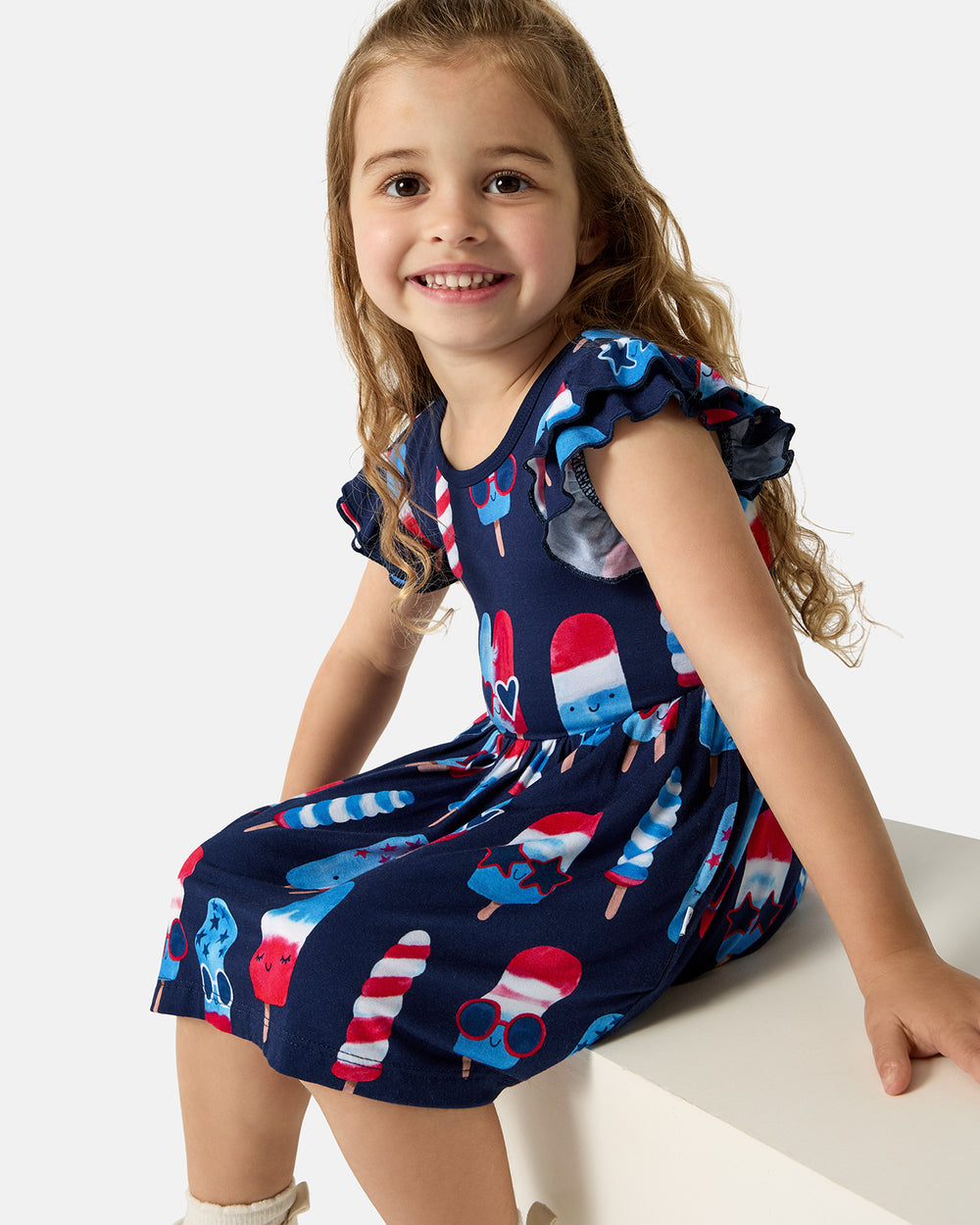Sitting girl wearing the Sparkle Treats Flutter Skater Dress