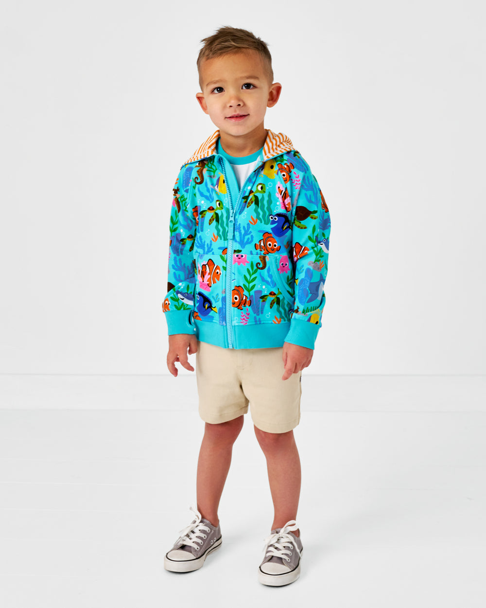 Standing child wearing the Disney Nemo's Reef Zip Hoodie with Light Khaki chino shorts