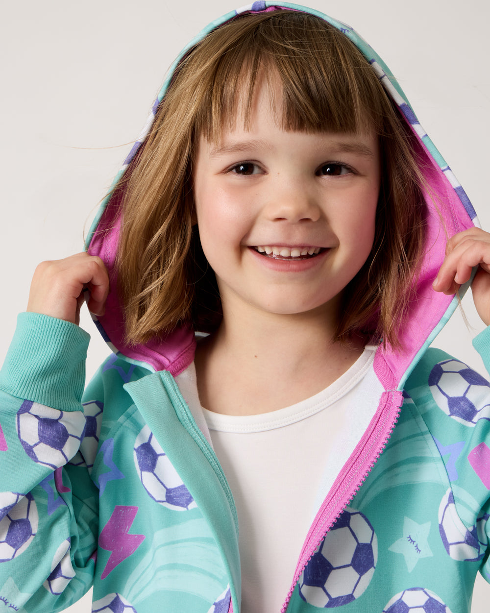 Girl wearing the Aqua Soccer Stars Zip Hoodie layered over a white tee