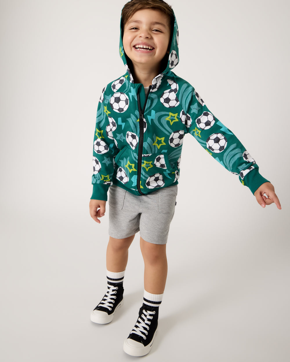 Boy wearing the Soccer Stars Zip Hoodie with gray shorts