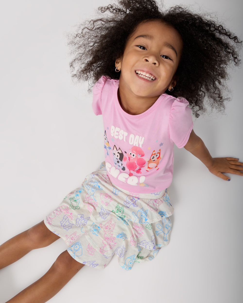 Sitting girl wearing the Bluey Best Day Ever Puff Sleeve Tee with a Bluey skort