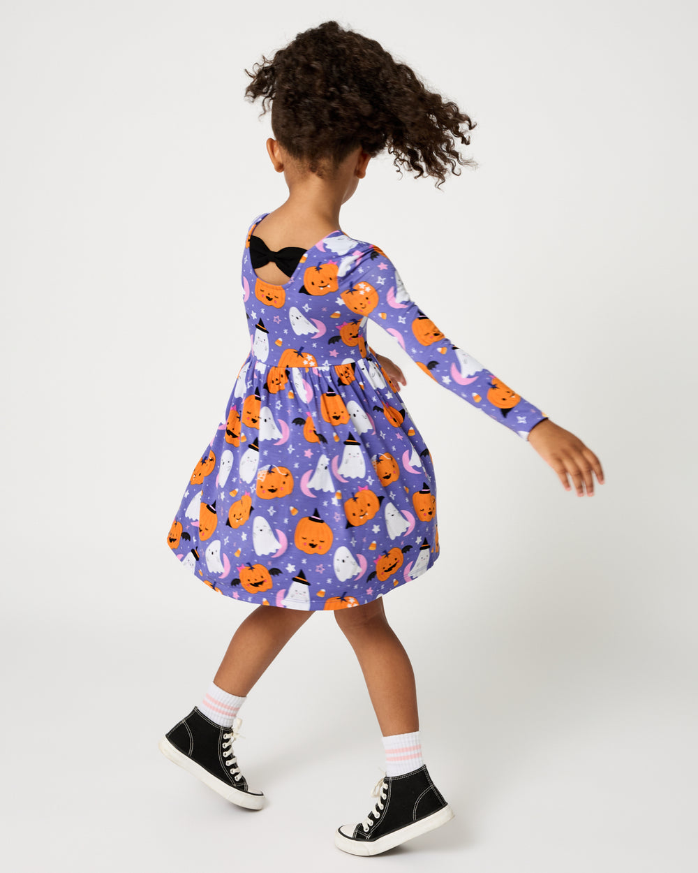 Back view of twirling girl wearing the Moonlit Magic Purple Bow Back Skater Dress