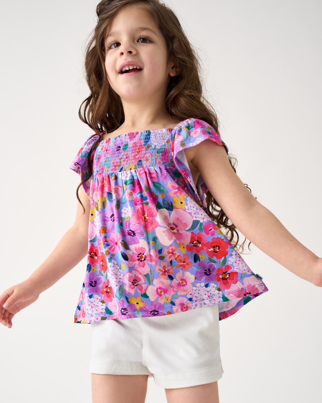 Girl wearing the Sweet Sprigs Smocked Flutter Top with white denim shorts