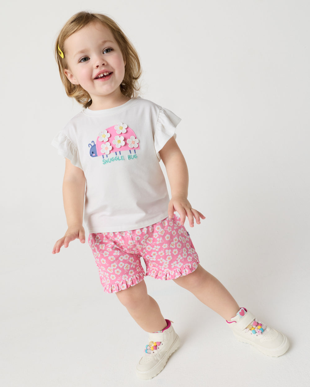Toddler wearing the Snuggle Bug Flutter Tee with pink floral shorts