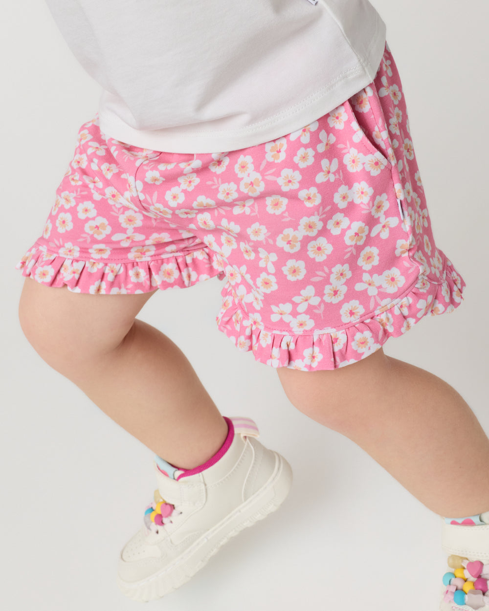Close up of child wearing the Sweet Pink Petals Ruffle Shorts with sneakers