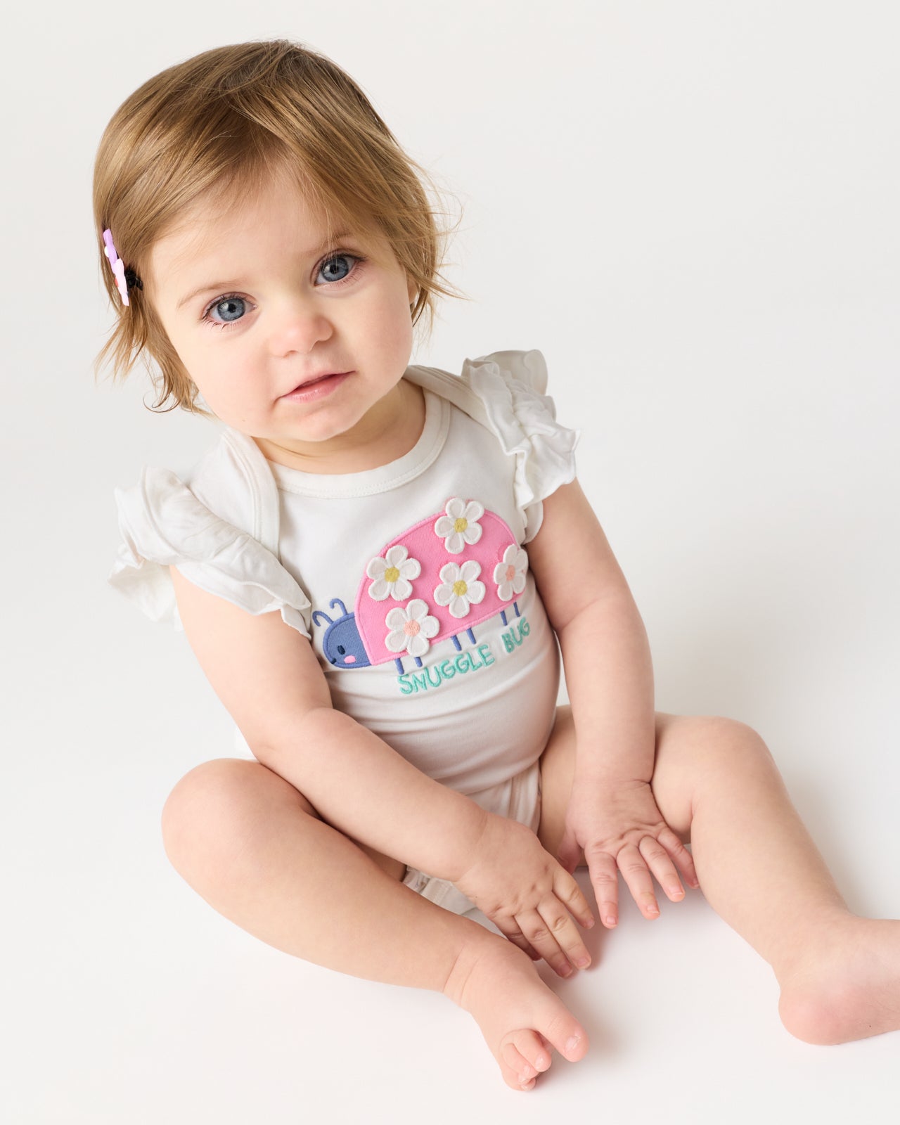 Sitting baby wearing the Snuggle Bug Flutter Bodysuit