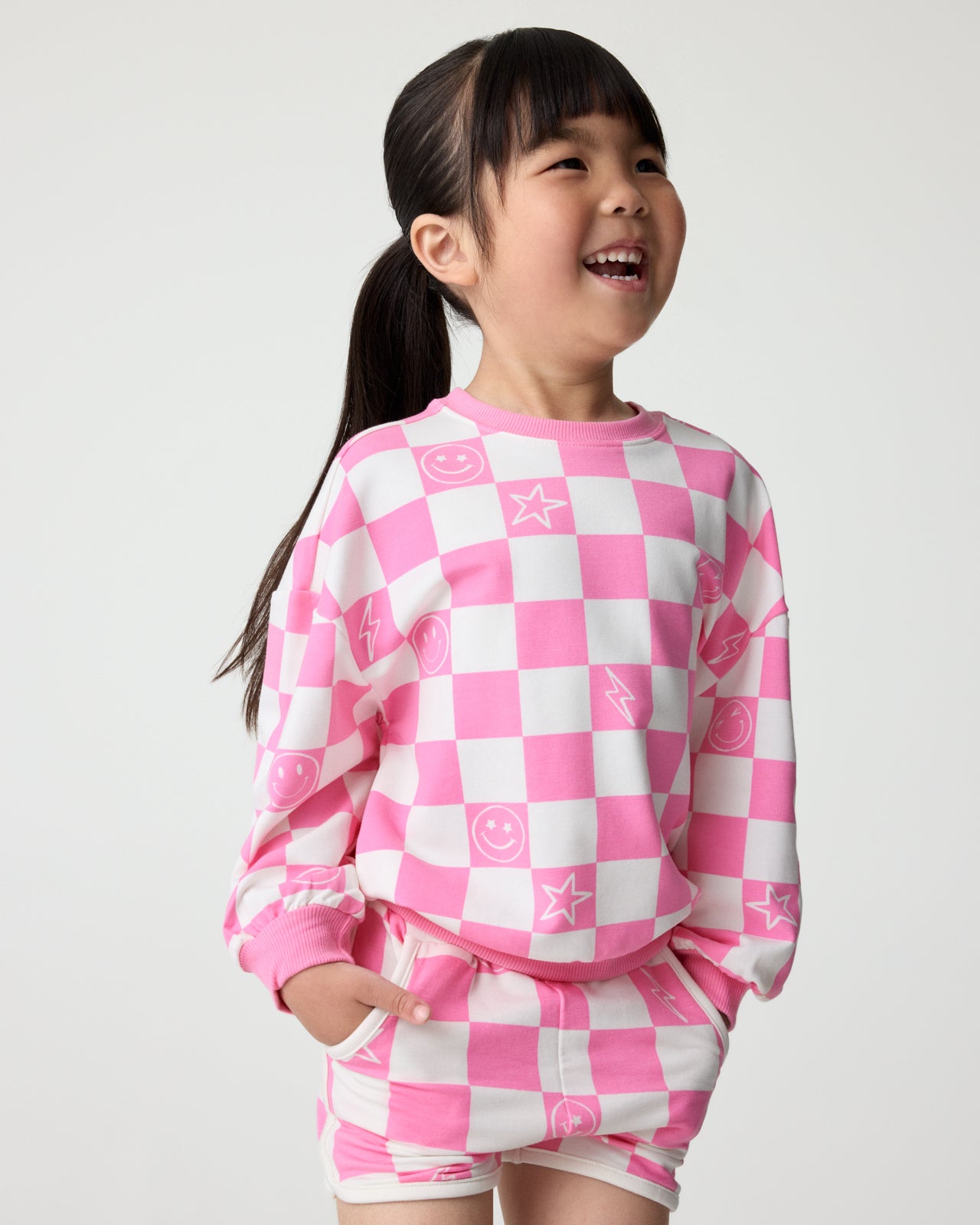 Girl wearing the Cheery Checks Pink Drop Shoulder Sweatshirt and Shorts