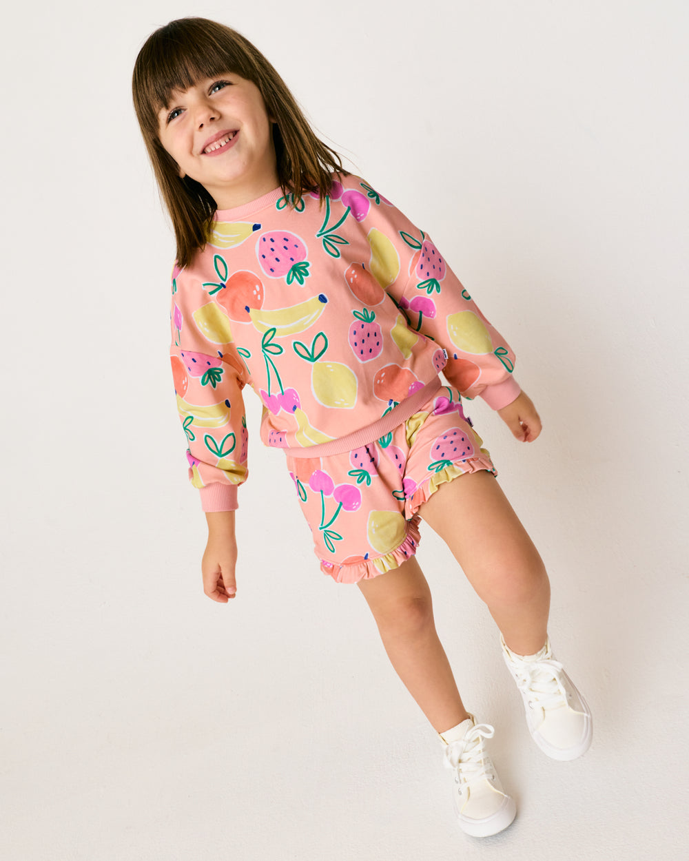 Girl wearing the Fruit Frenzy Ruffle Shorts with a matching crewneck