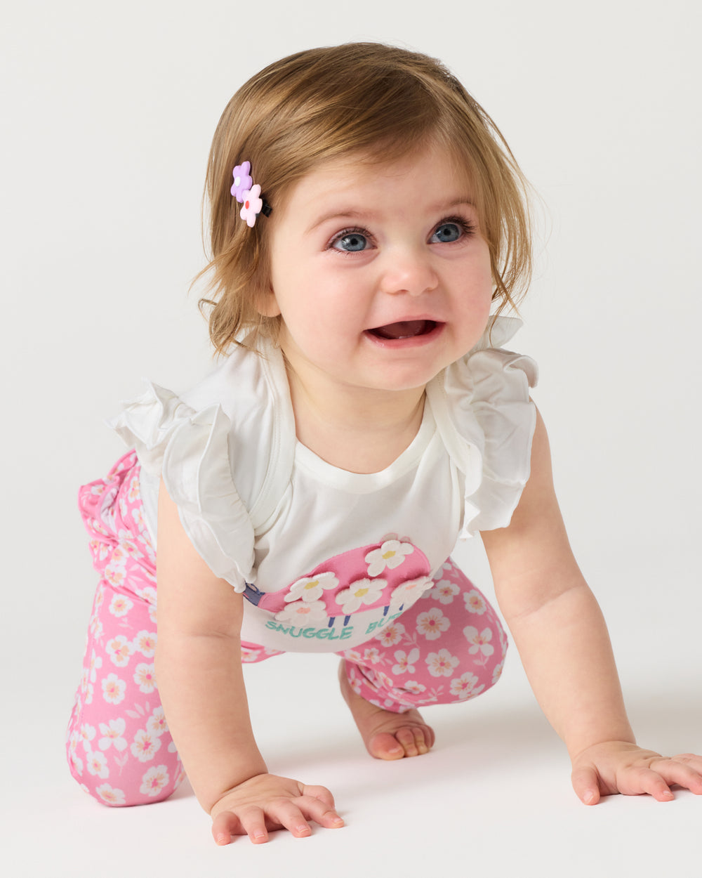 Crawling baby wearing the Sweet Pink Petals Ruffle Legging and Snuggle Bug bodysuit