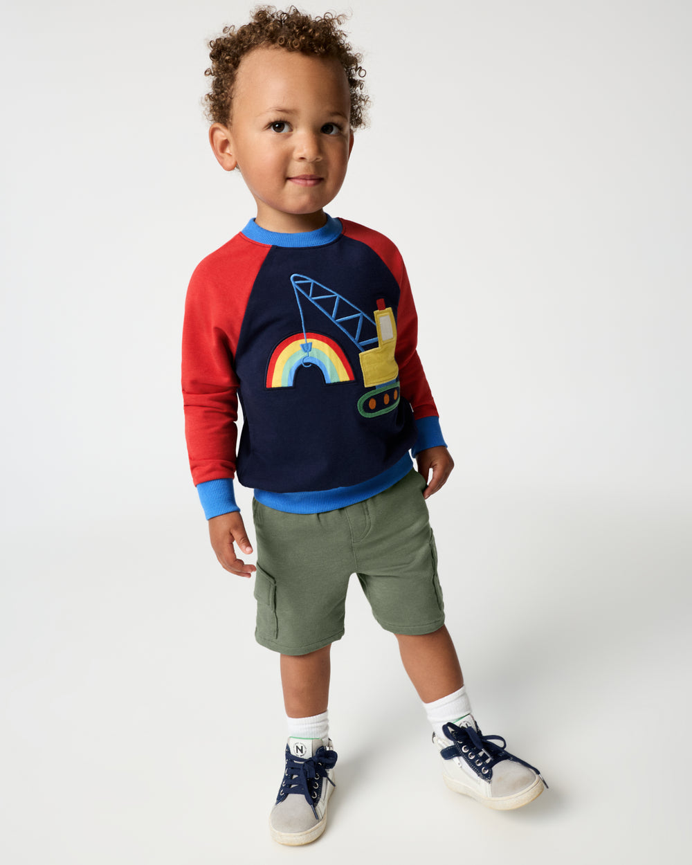 Boy wearing the Rainbow Trucks Crewneck Sweatshirt with green shorts