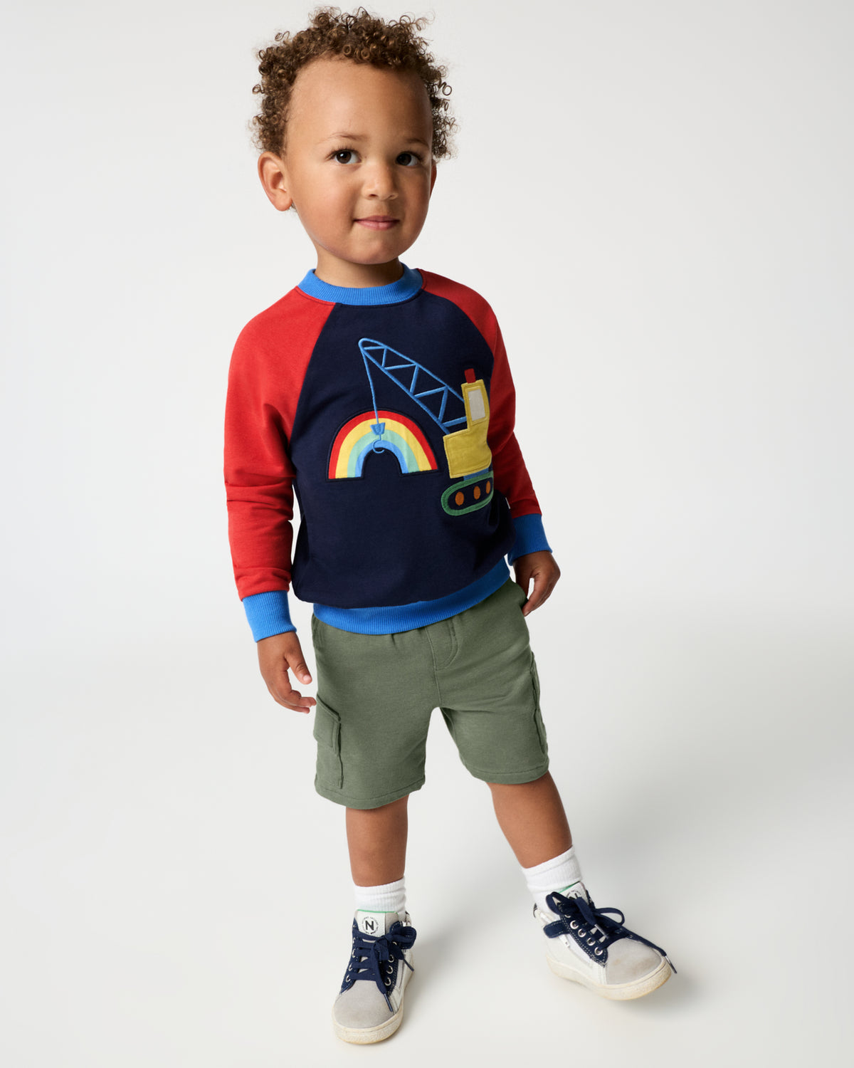 Boy wearing the Rainbow Trucks Crewneck Sweatshirt with green shorts