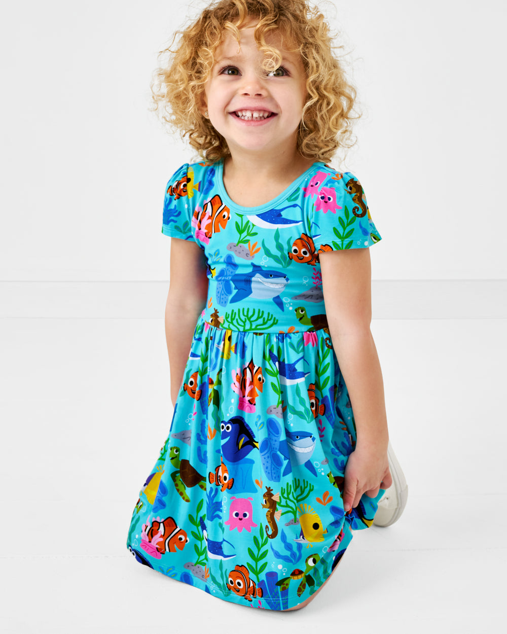 Kneeling girl wearing the Pixar Nemo's Reef Skater Dress