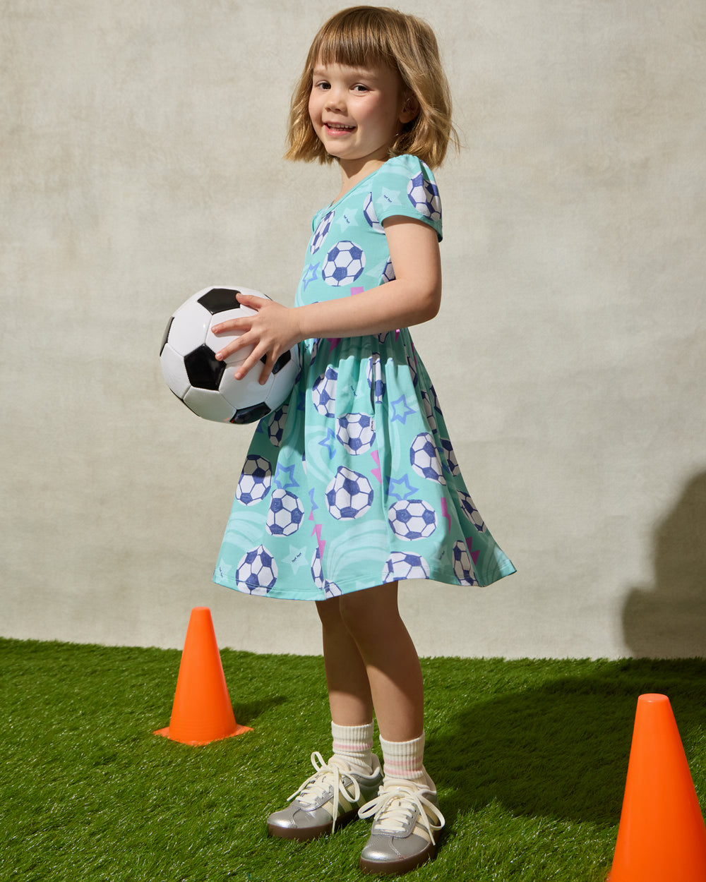 Girl wearing the Aqua Soccer Stars Skater Dress holding a soccer ball