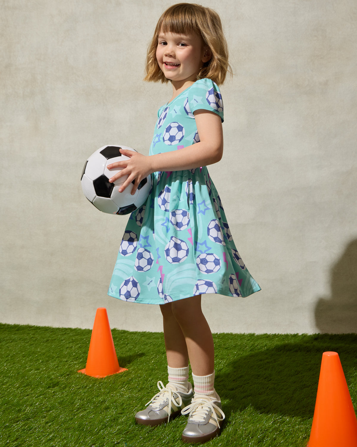 Girl wearing the Aqua Soccer Stars Skater Dress holding a soccer ball