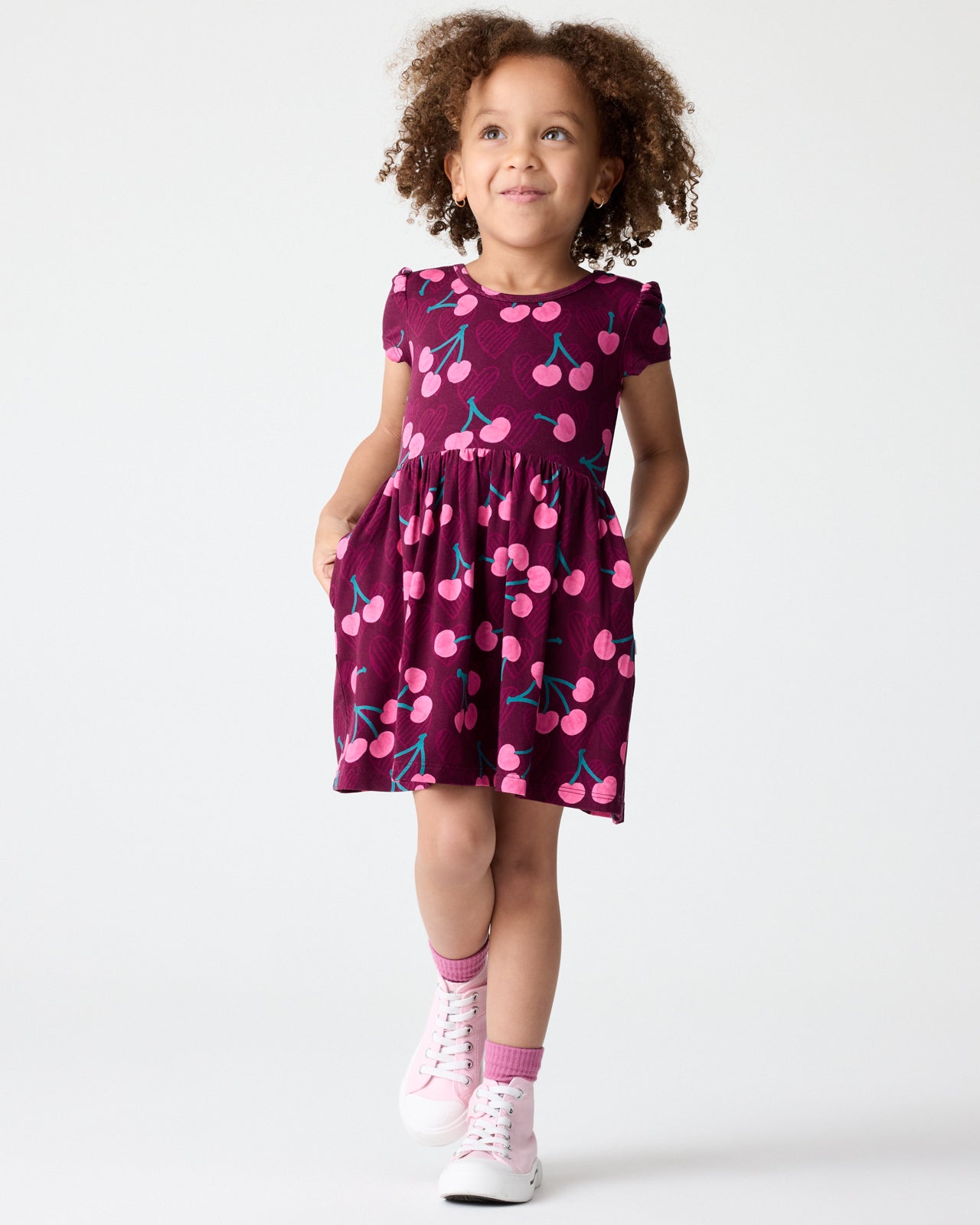 Girl wearing the Cherry Charm Skater Dress with pink sneakers