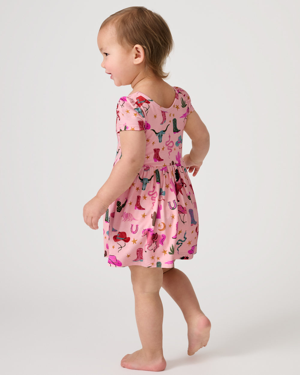 Walking toddler wearing the Pink Rancher Roundup Skater Dress with Bodysuit