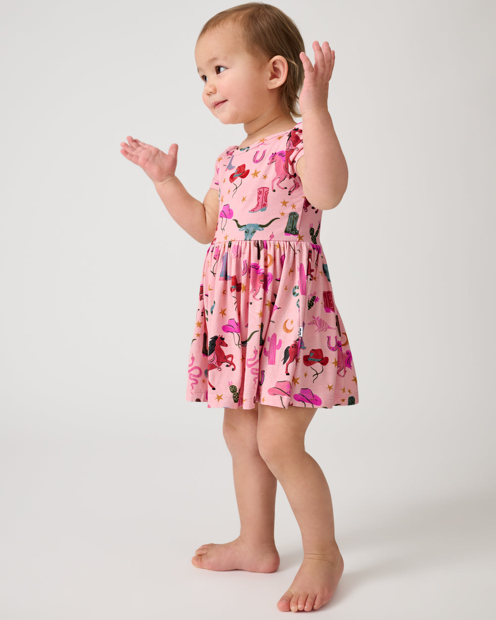 Standing child wearing the Pink Rancher Roundup Skater Dress with Bodysuit