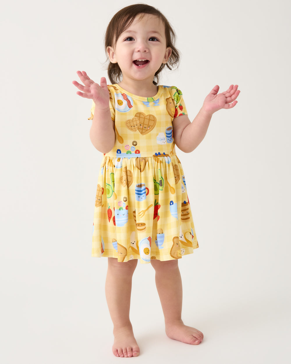 Clapping toddler wearing the Breakfast Bunch Skater Dress with Bodysuit