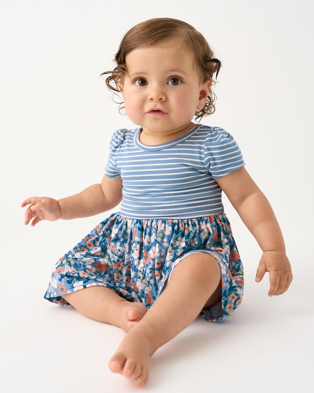 Sitting baby girl wearing the Petite Petals Skater Dress with Bodysuit