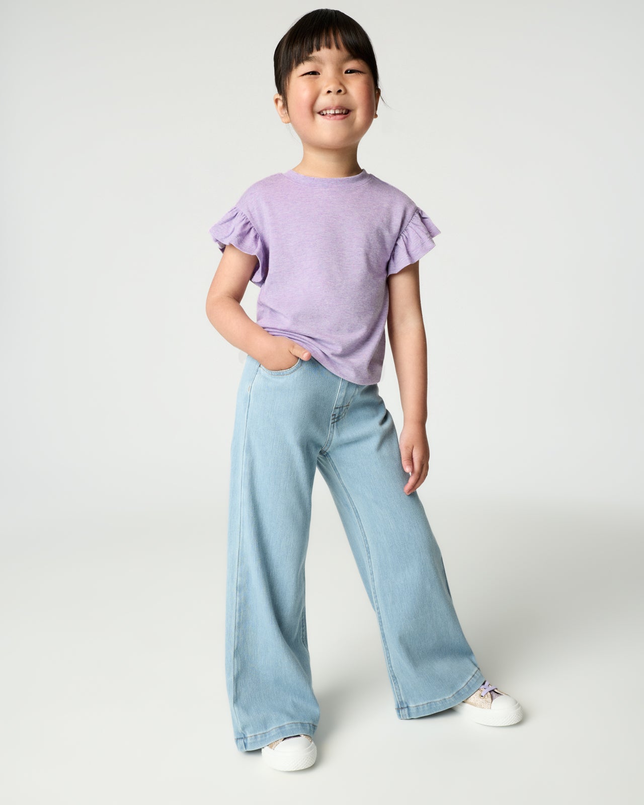 Girl wearing the Heather Lavender Flutter Tee with wide leg denim pants