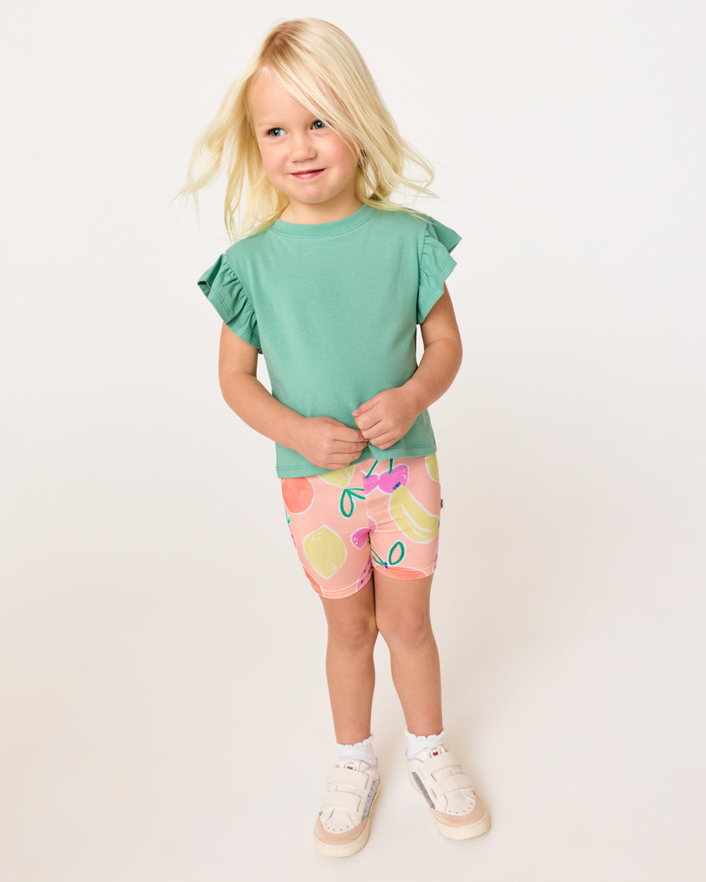 Girl wearing the Fruit Frenzy Bike Shorts with a green top