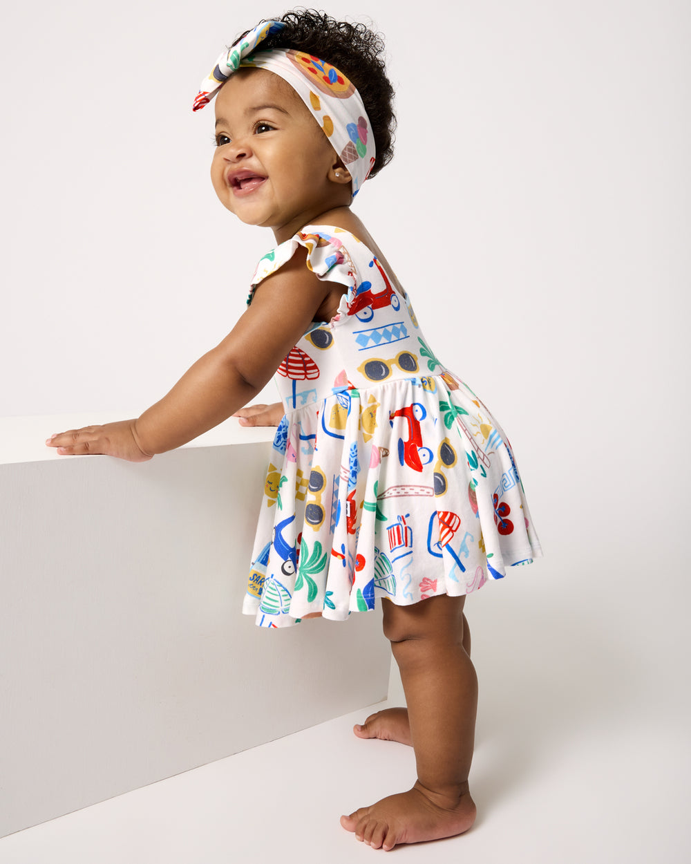 Standing girl wearing the Ciao Bella Twirl Dress with Bodysuit and Bow Headband