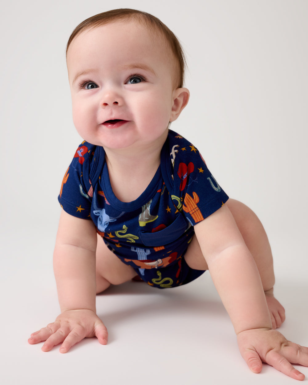 Crawling baby wearing the Blue Rancher Roundup Pocket Bodysuit