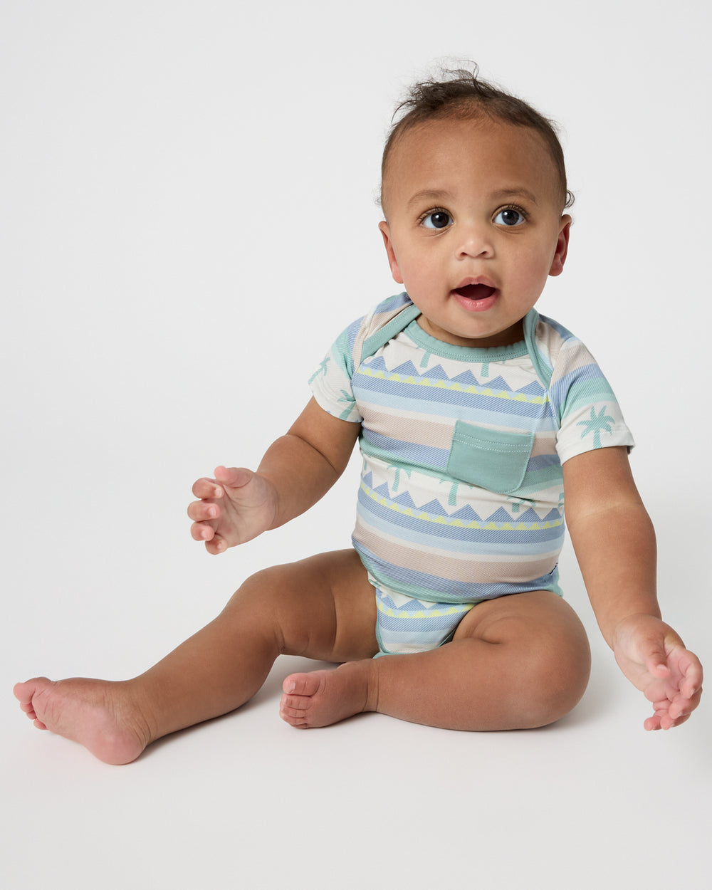 Sitting newborn wearing the Swell Stripes Pocket Bodysuit 