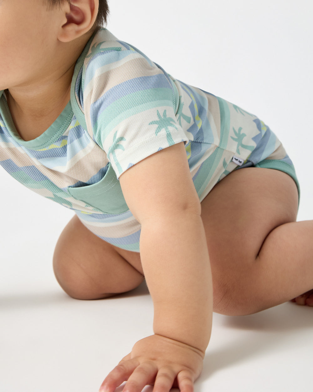 Close up of crawling baby wearing the Swell Stripes Pocket Bodysuit