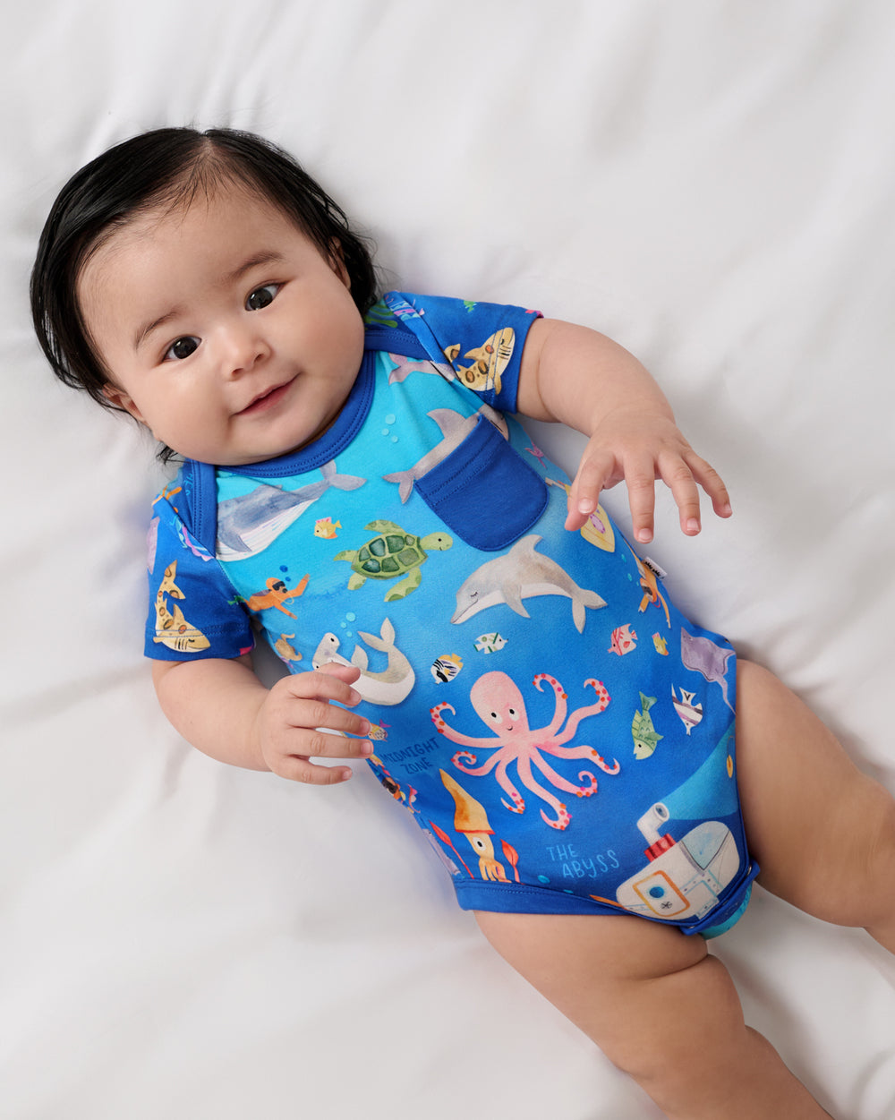 Aerial view of baby wearing the Underwater Discovery Pocket Bodysuit