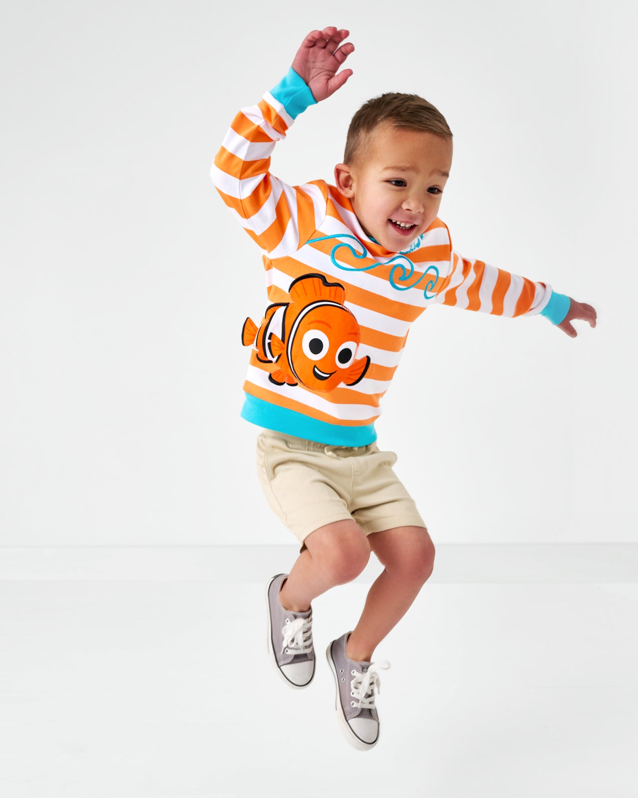 Jumping child wearing the Disney Nemo Crewneck Sweatshirt and light khaki chino shorts