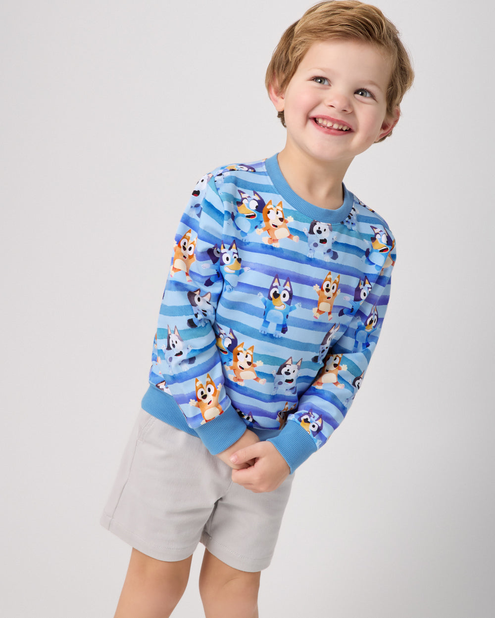 Boy wearing the Bluey Dance All Day Crewneck Sweatshirt with gray chino shorts