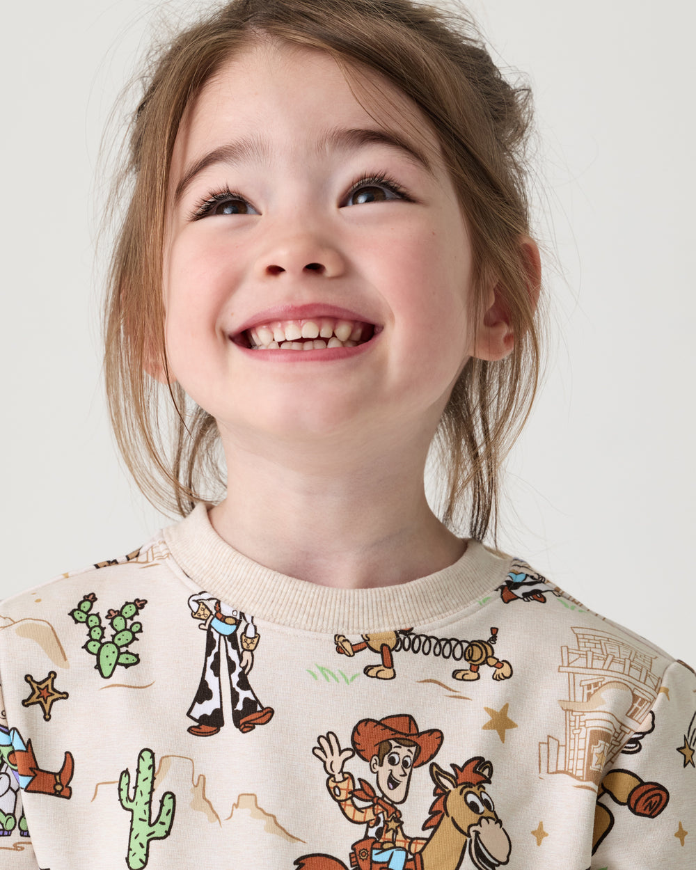 Close up of girl wearing the Disney & Pixar Woody's Wild West Crewneck Sweatshirt