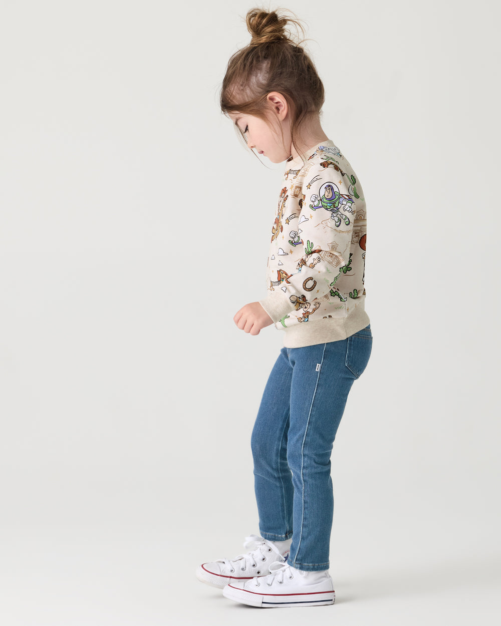 Girl wearing the Disney & Pixar Woody's Wild West Crewneck Sweatshirt with denim pants