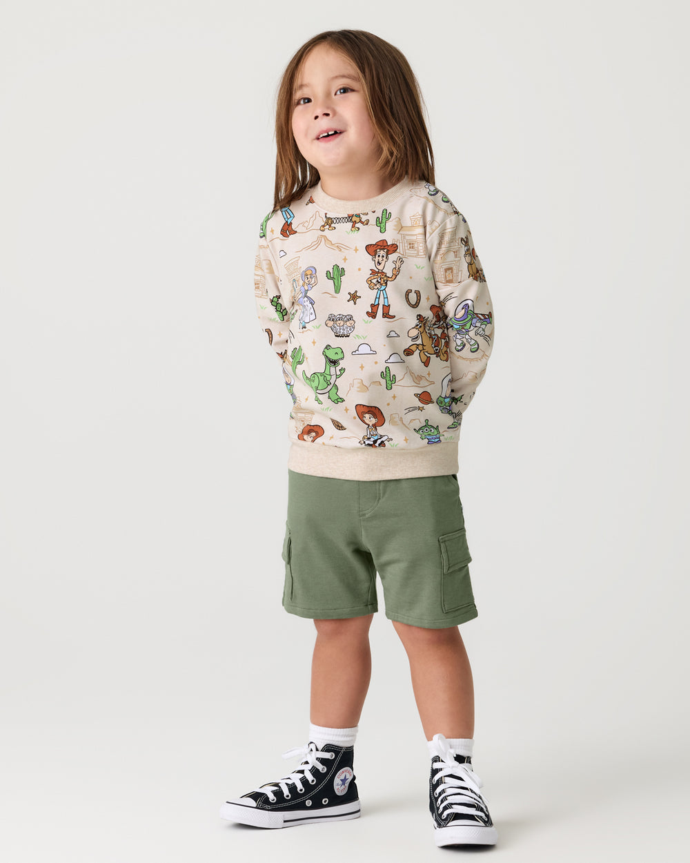 Boy wearing the Disney & Pixar Woody's Wild West Crewneck Sweatshirt with green shorts