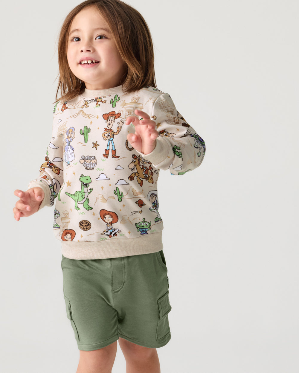 Child wearing the Disney & Pixar Woody's Wild West Crewneck Sweatshirt with cargo shorts