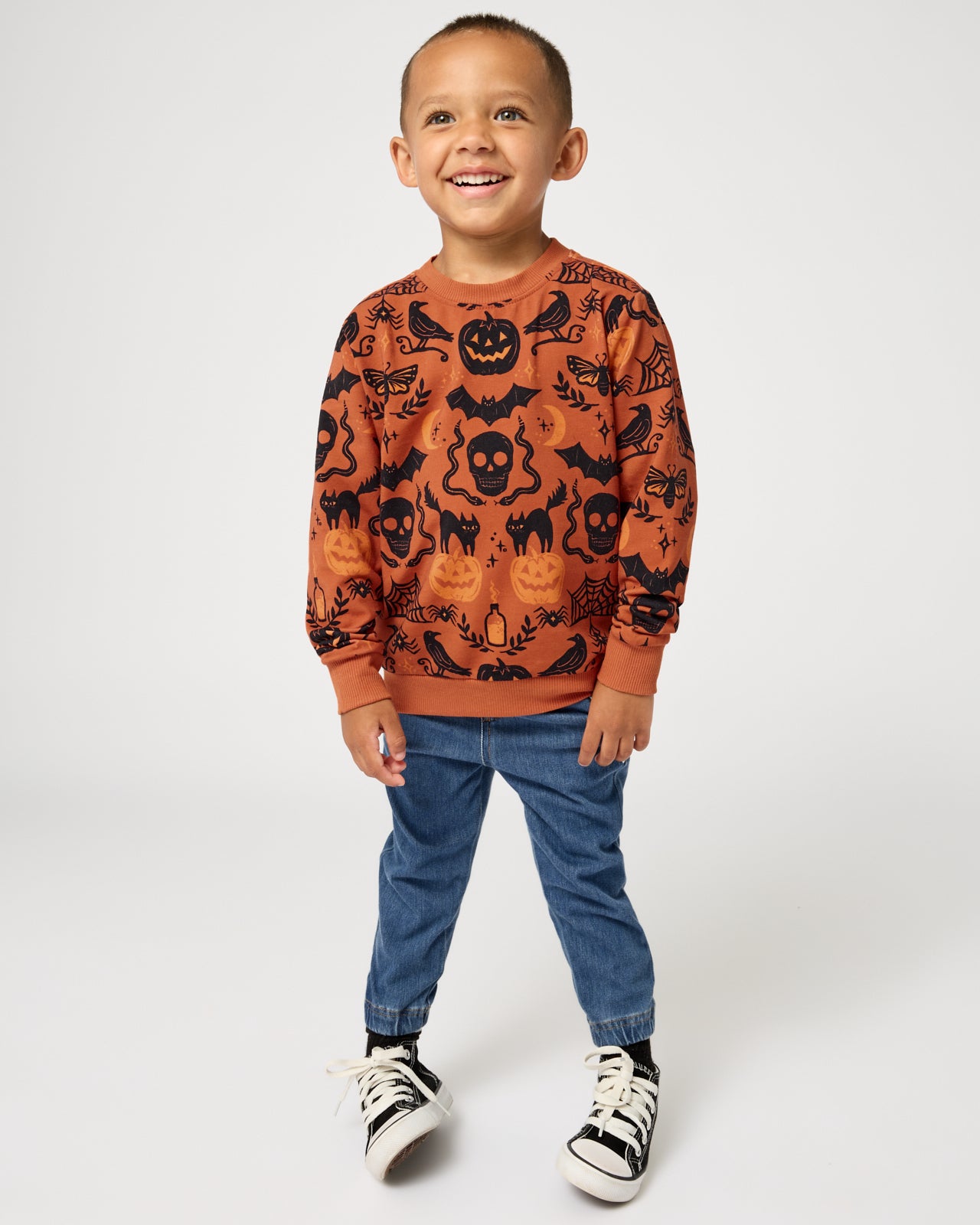 Boy wearing the Midnight Mischief Crewneck Sweatshirt with blue denim joggers