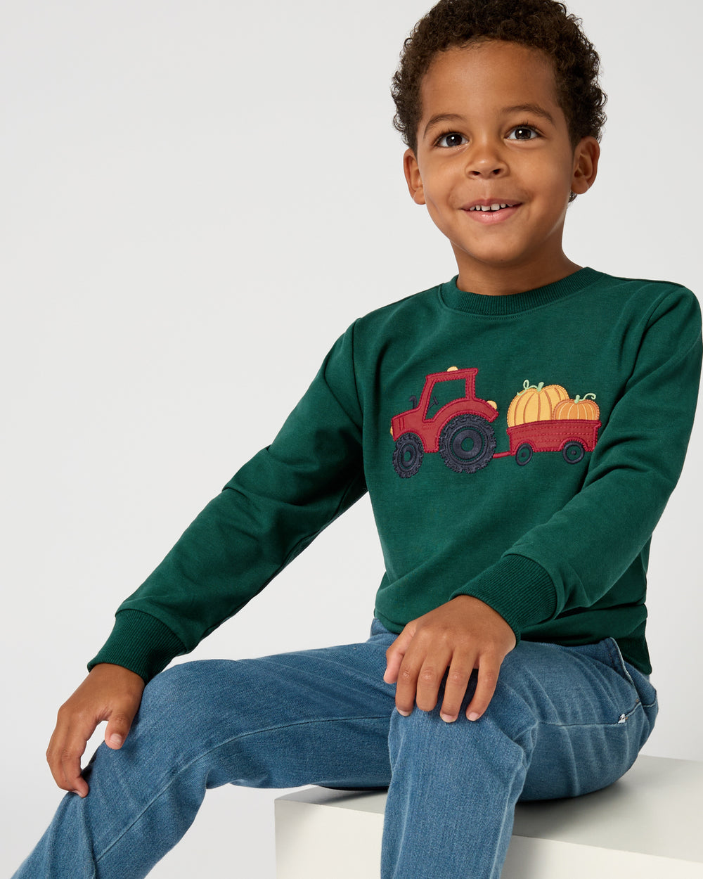 Sitting boy wearing the Tractor Ride Crewneck Sweatshirt 