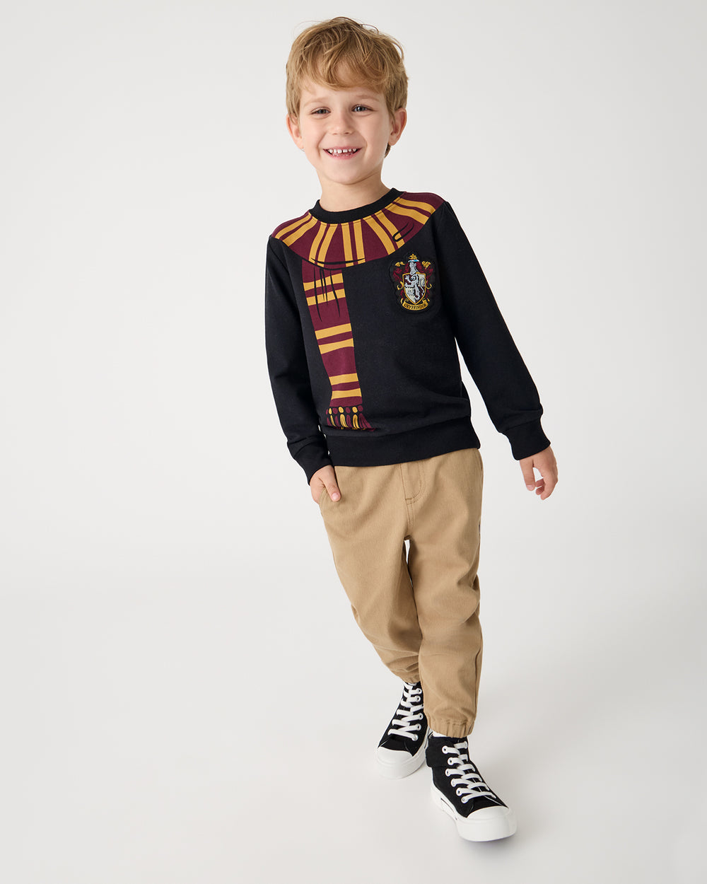 Boy wearing the Harry Potter™ Gryffindor Crewneck Sweatshirt with khaki joggers