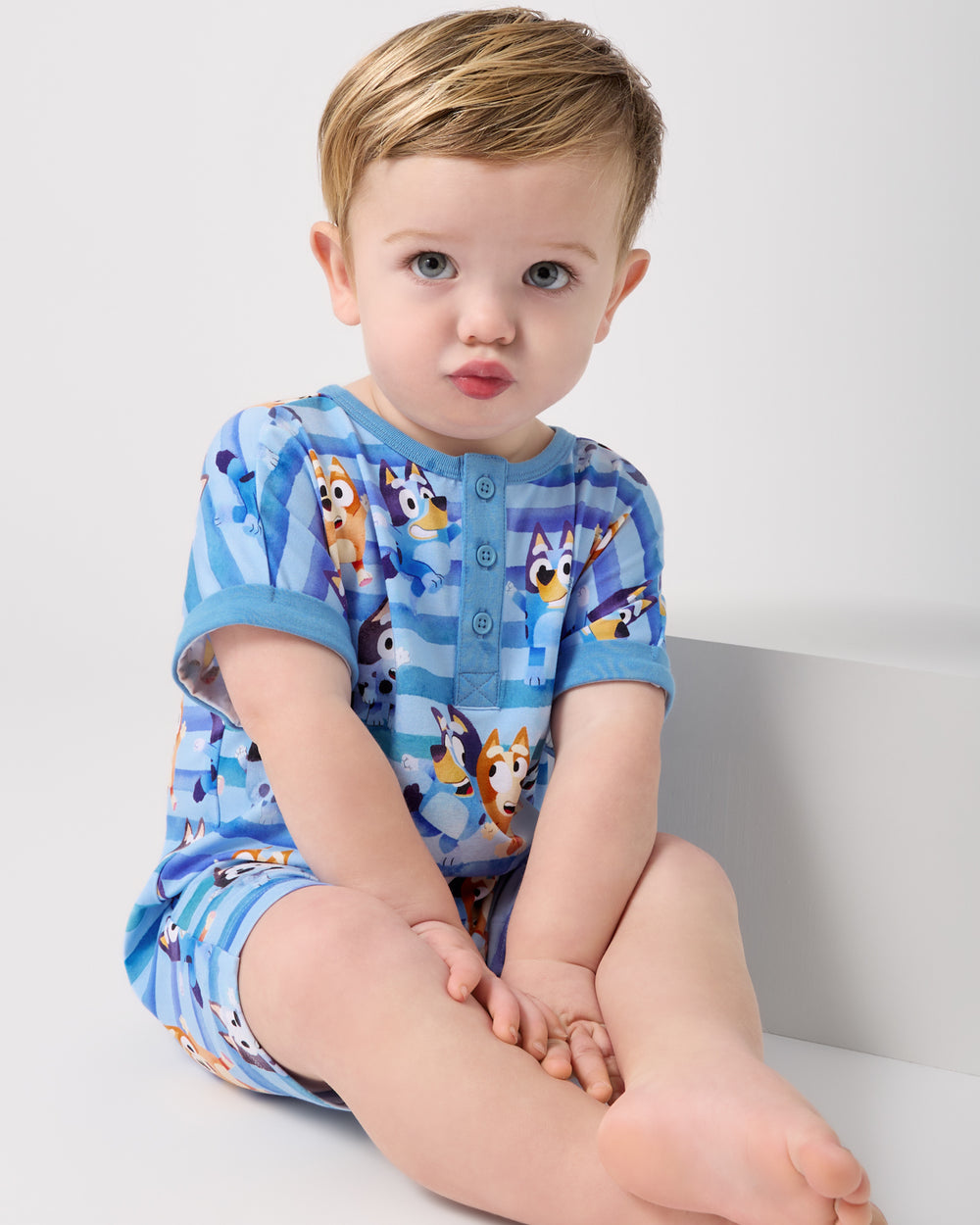 Sitting boy wearing the Bluey Dance All Day Dolman Henley Romper