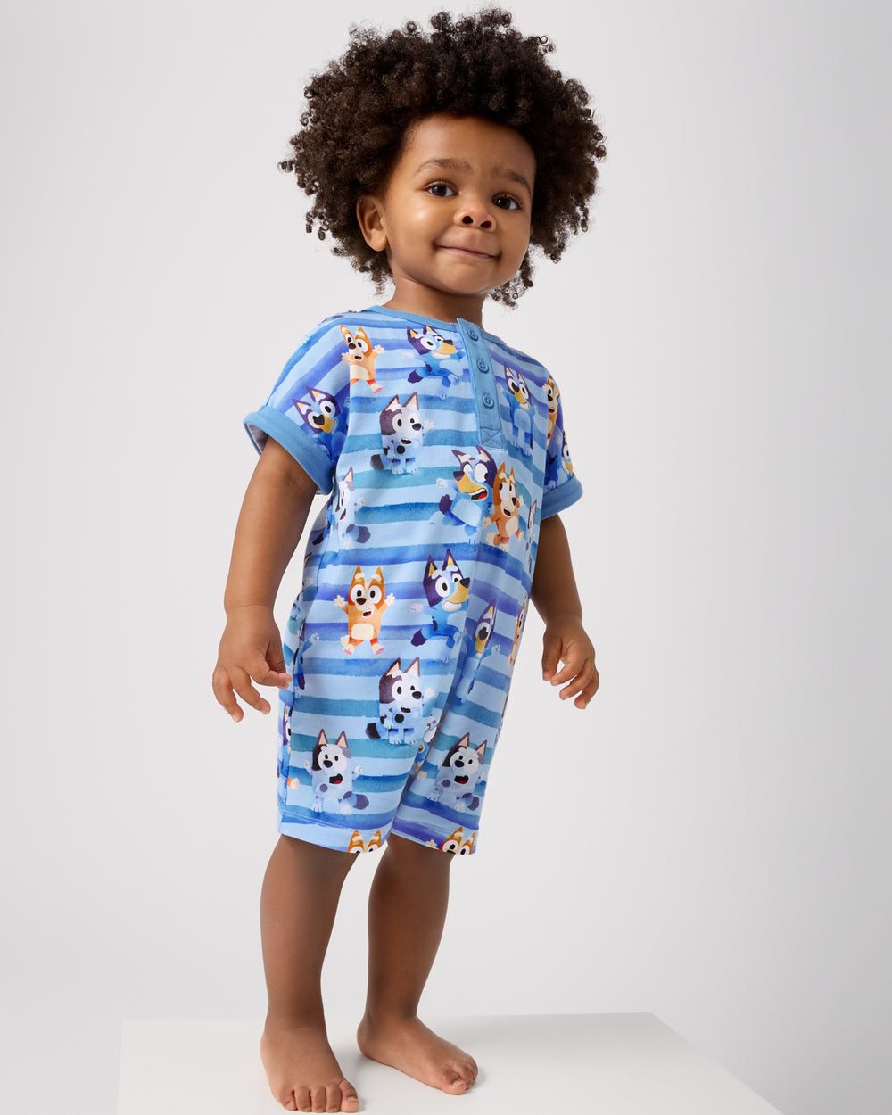 Standing toddler wearing the Bluey Dance All Day Dolman Henley Romper