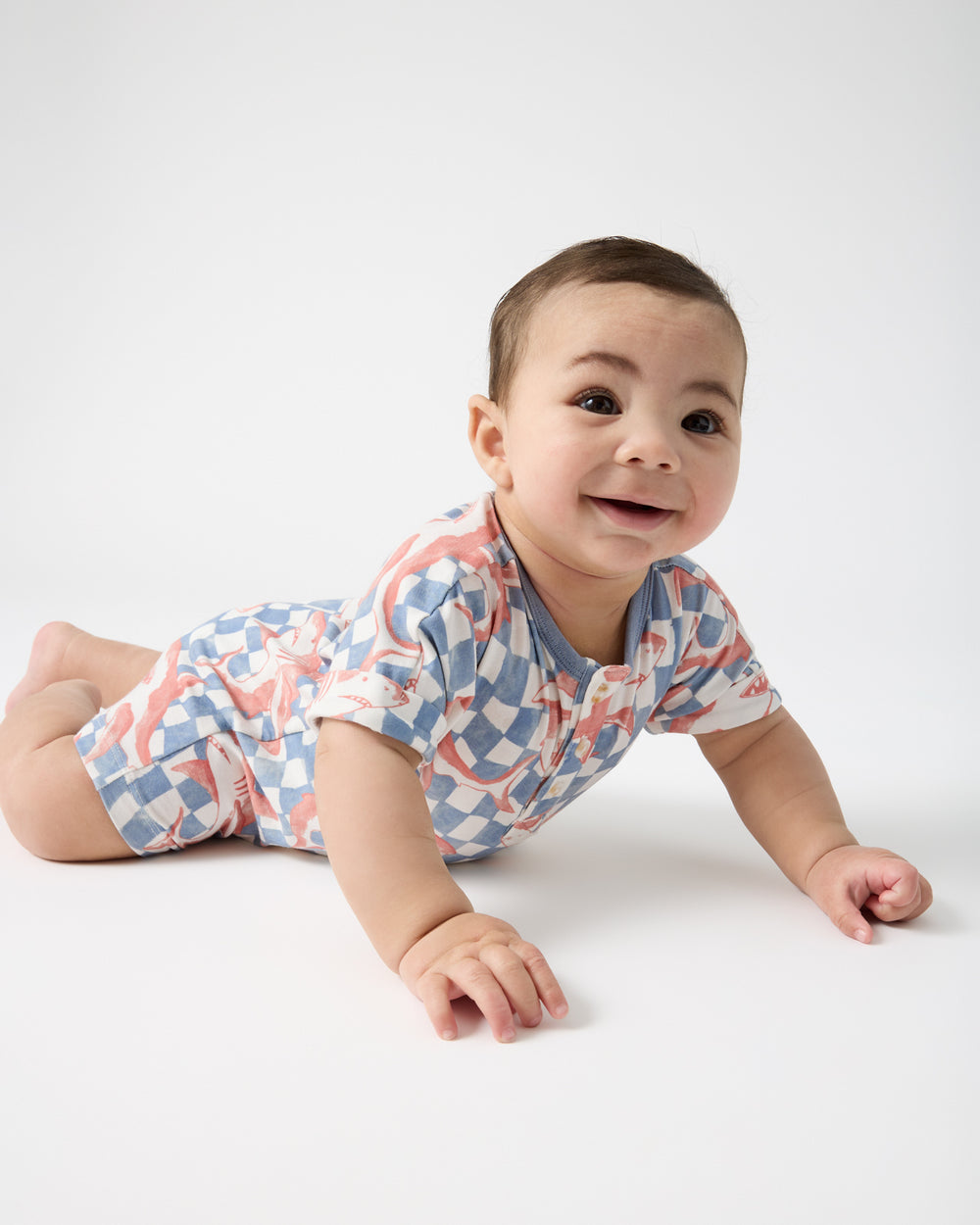 Baby on his tummy wearing the Shark Fin Checks Dolman Henley Romper