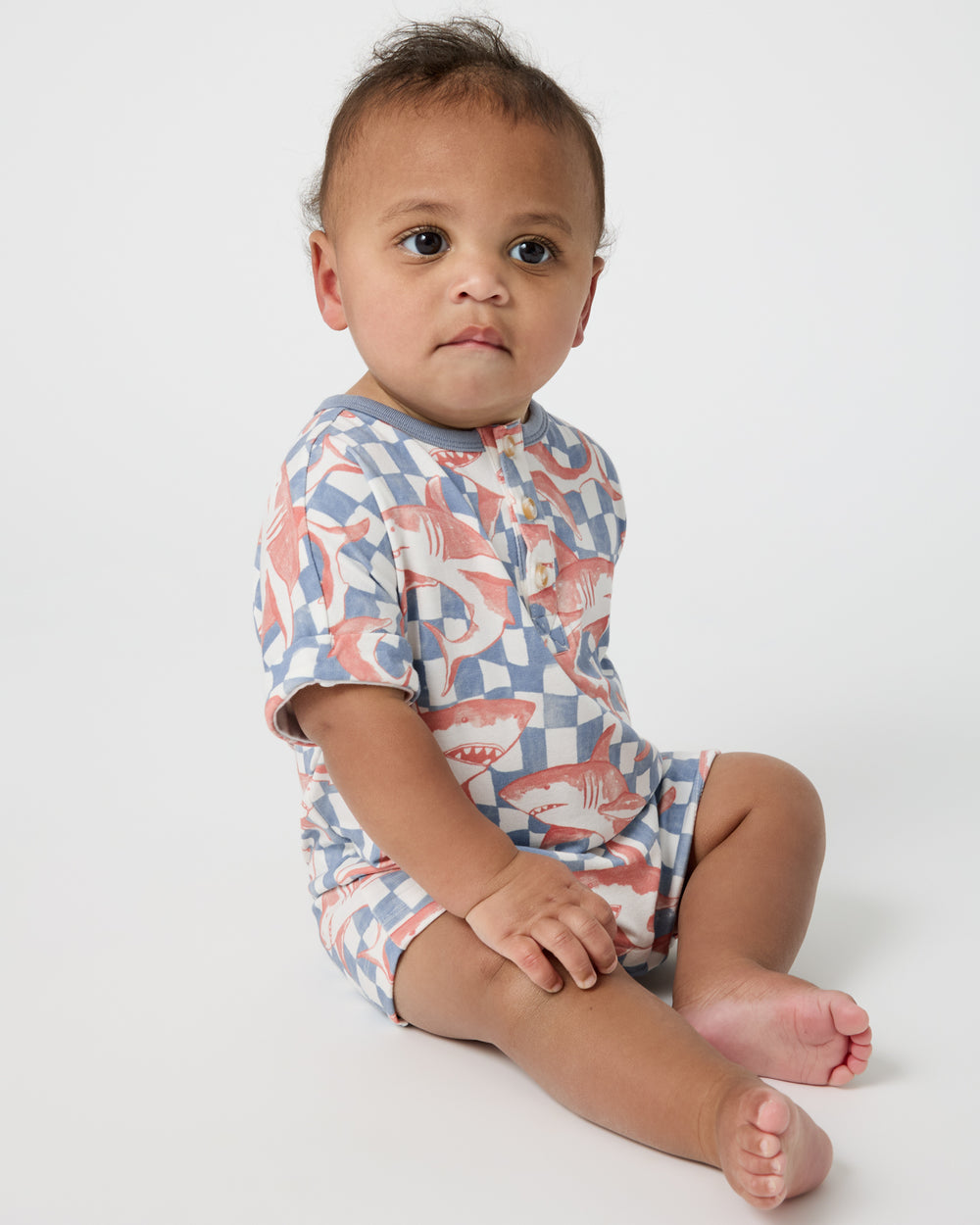 Sitting baby wearing the Shark Fin Checks Dolman Henley Romper