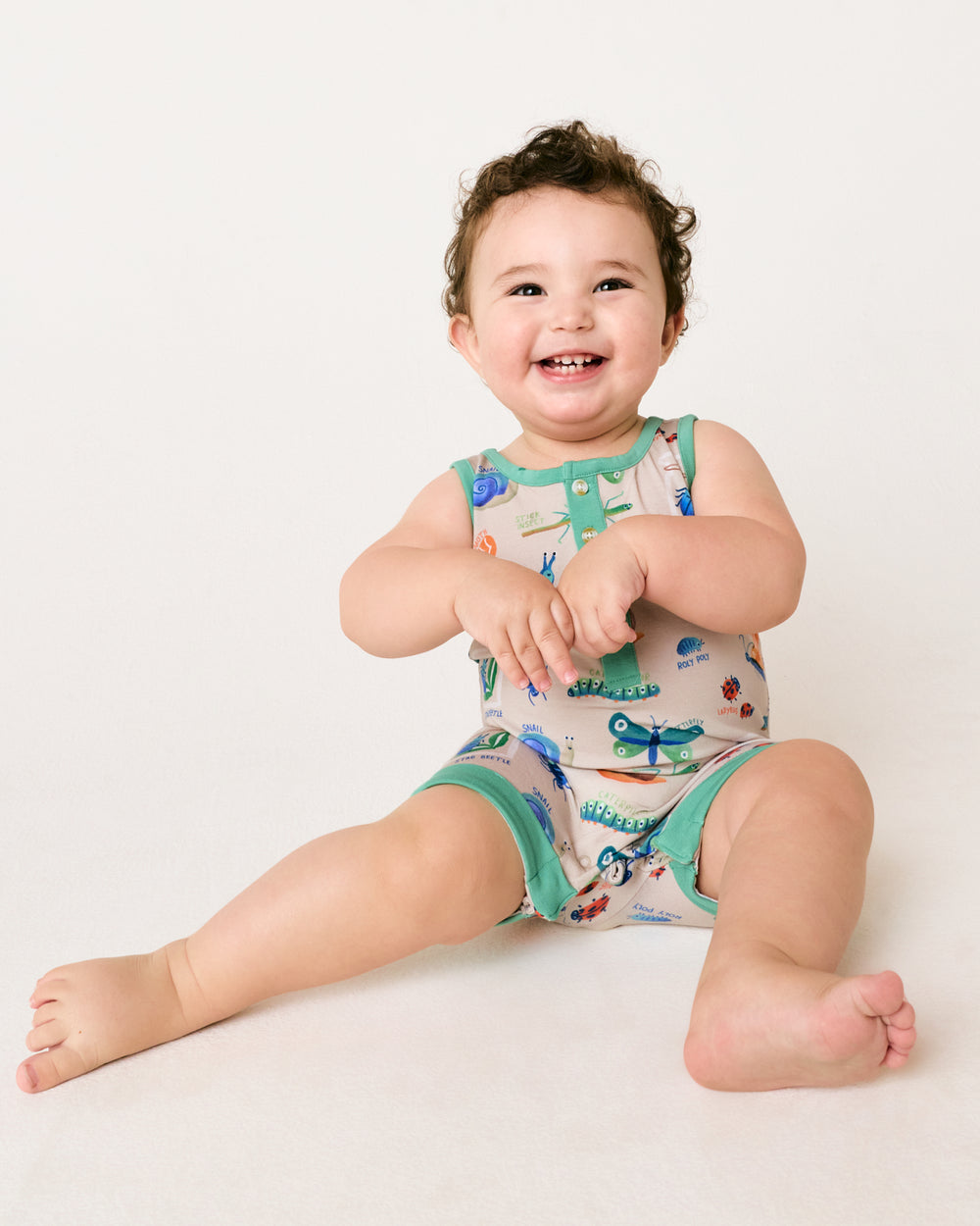 Sitting toddler wearing the Nature Notes Henley Romper