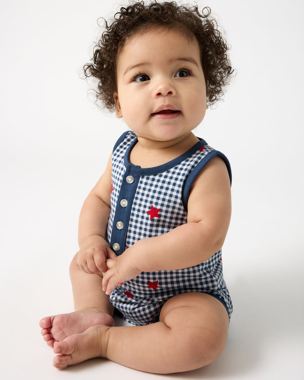 Sitting newborn wearing the Blue Ribbon Gingham Henley Romper