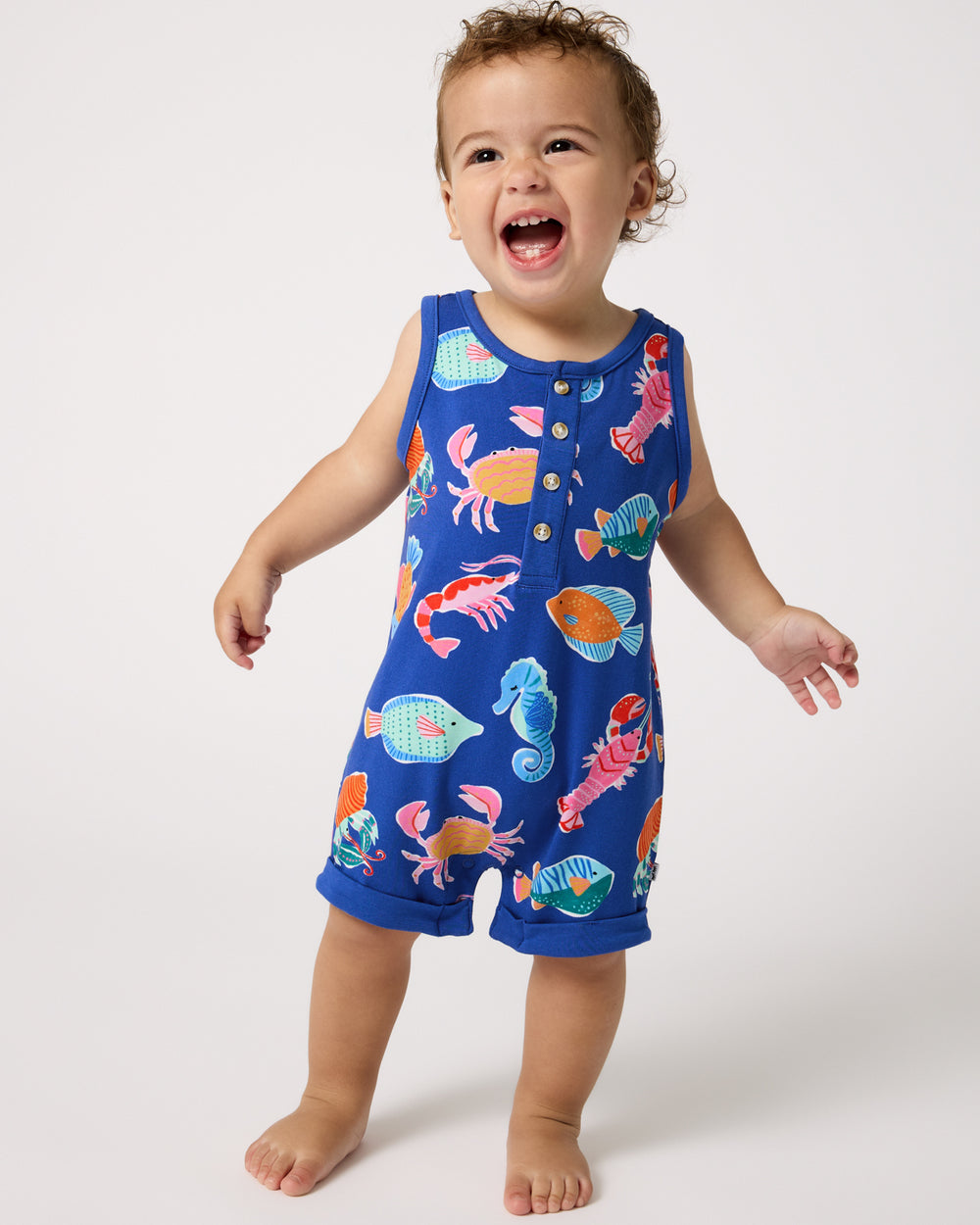 Standing toddler wearing the Tidepool Party Henley Romper